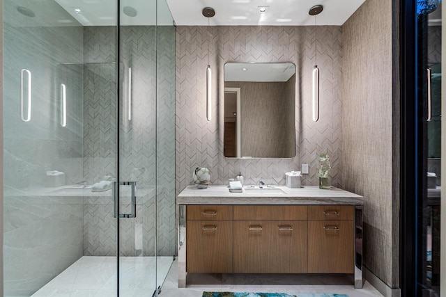 bathroom featuring walk in shower, vanity, and tile walls