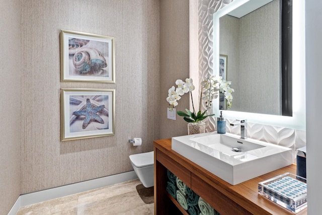 half bath featuring wallpapered walls, baseboards, toilet, wood finished floors, and vanity