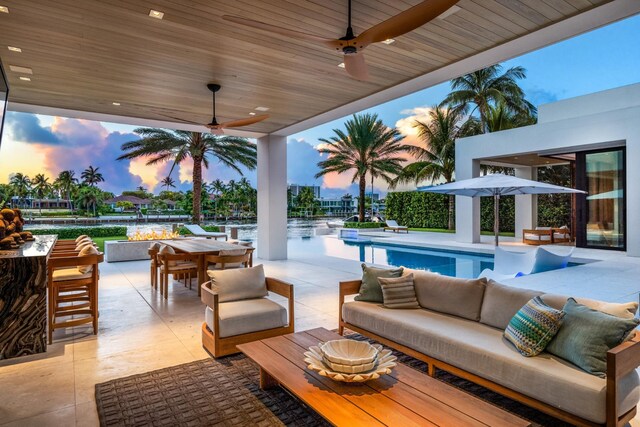 patio terrace at dusk featuring a bar, ceiling fan, and an outdoor living space