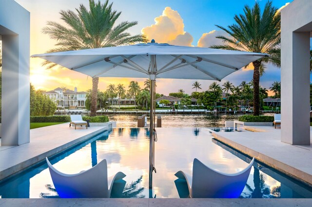 pool at dusk featuring a patio