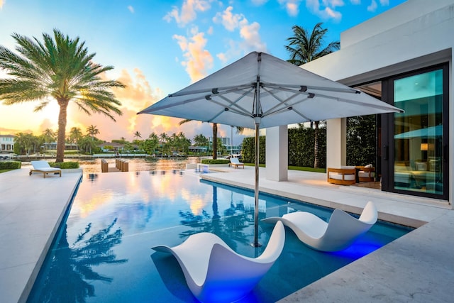 pool at dusk featuring a patio area and an outdoor pool