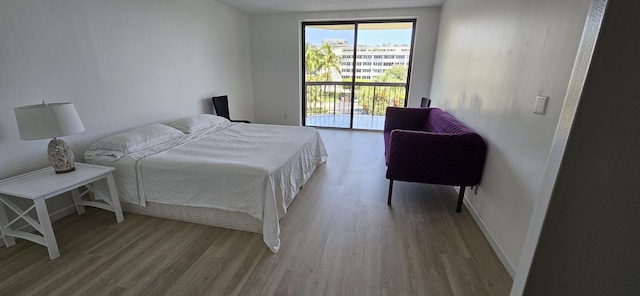 bedroom with a textured ceiling, access to outside, and light hardwood / wood-style flooring