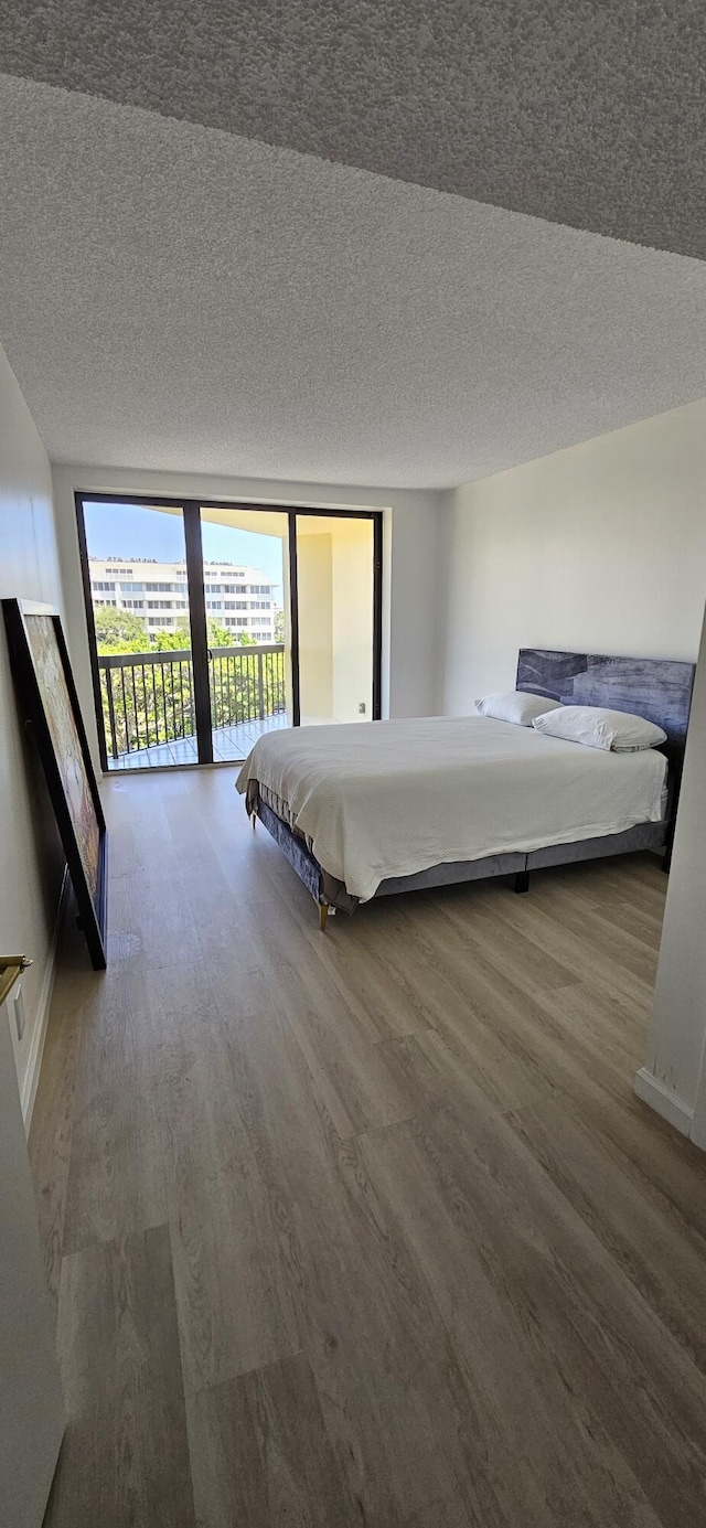 unfurnished bedroom featuring access to outside, floor to ceiling windows, wood-type flooring, and a textured ceiling