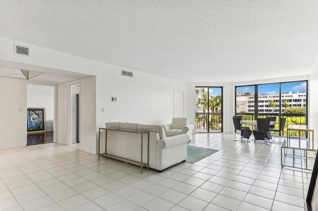 unfurnished living room with light tile patterned floors, visible vents, and a textured ceiling