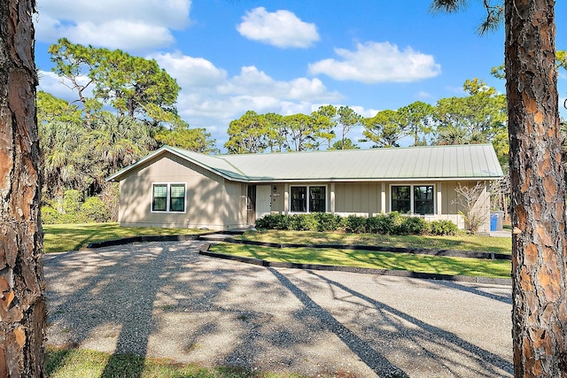 ranch-style house featuring metal roof and a front lawn