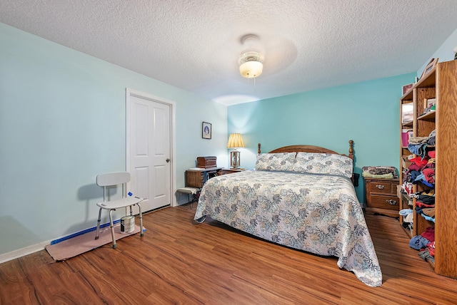 bedroom with ceiling fan, wood-type flooring, and a textured ceiling