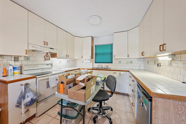 kitchen featuring white electric range oven, light tile patterned flooring, white cabinets, a sink, and under cabinet range hood