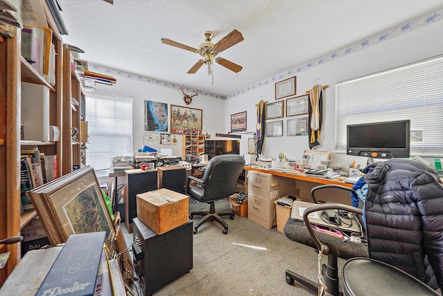 carpeted home office with a textured ceiling and ceiling fan