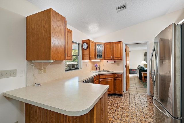 kitchen featuring a textured ceiling, sink, stainless steel refrigerator, kitchen peninsula, and vaulted ceiling