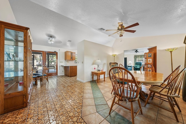 dining area featuring vaulted ceiling, ceiling fan, a textured ceiling, and french doors