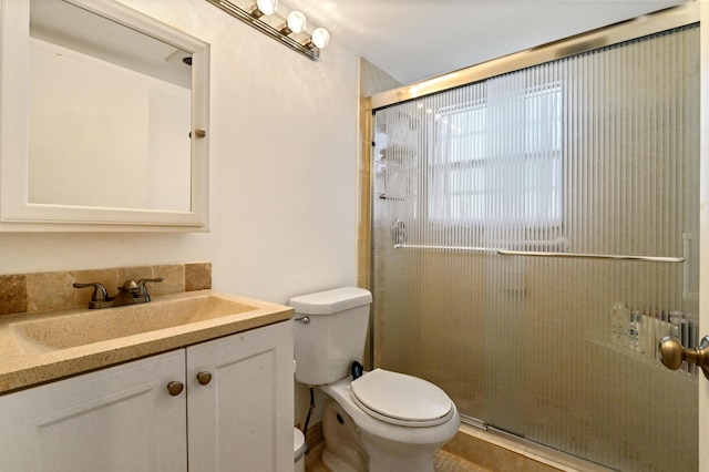 bathroom featuring a shower with door, vanity, and toilet