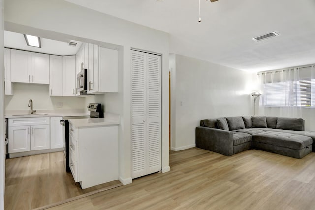 living room featuring sink, light hardwood / wood-style flooring, and ceiling fan