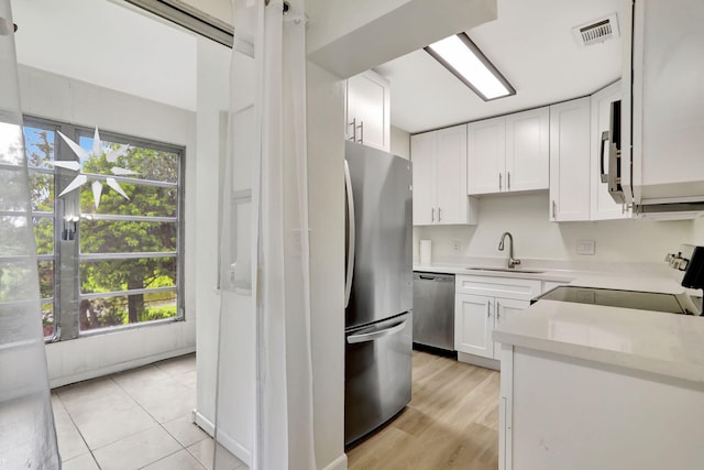 kitchen with white cabinetry, light hardwood / wood-style flooring, stainless steel appliances, and a healthy amount of sunlight