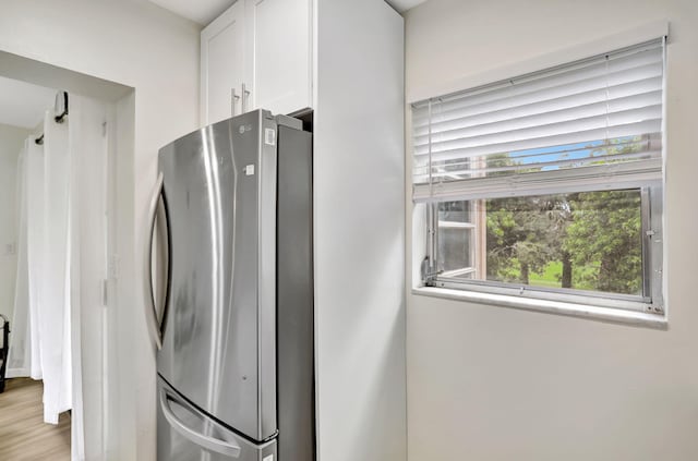 kitchen with white cabinets, light hardwood / wood-style floors, and stainless steel refrigerator