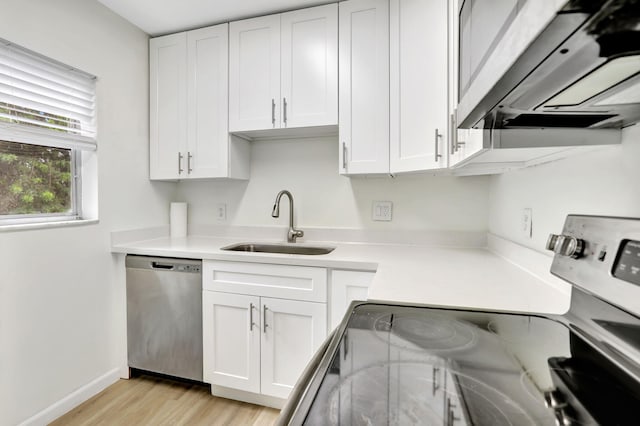 kitchen featuring range, light hardwood / wood-style flooring, sink, stainless steel dishwasher, and white cabinetry