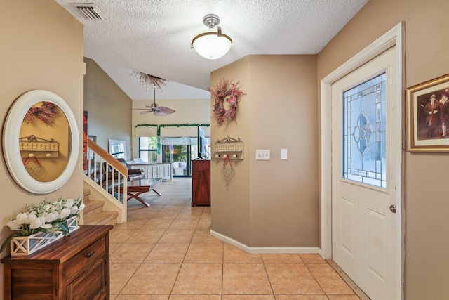 tiled entrance foyer with vaulted ceiling, ceiling fan, and a textured ceiling