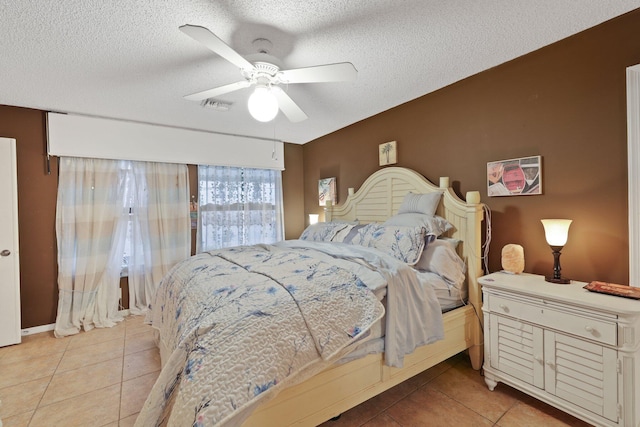 tiled bedroom with ceiling fan and a textured ceiling