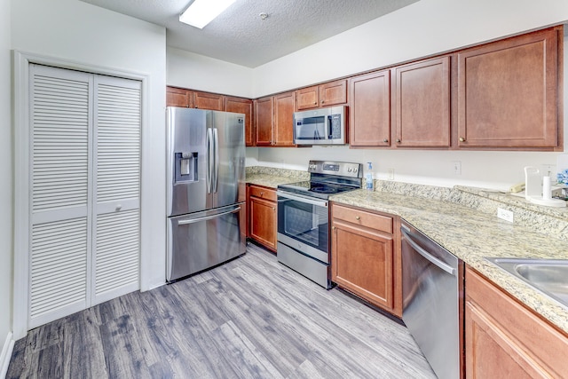 kitchen featuring light hardwood / wood-style floors, appliances with stainless steel finishes, and a textured ceiling