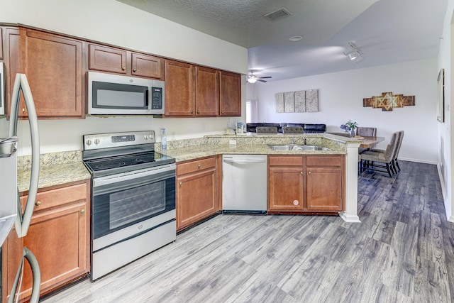 kitchen featuring appliances with stainless steel finishes, light hardwood / wood-style flooring, sink, kitchen peninsula, and ceiling fan