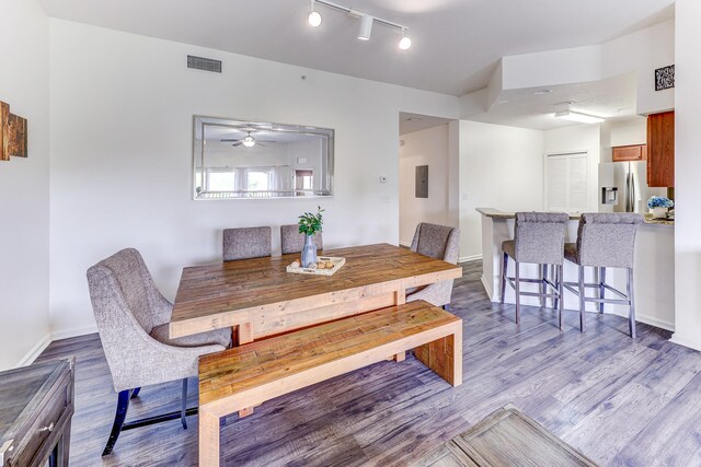 dining space with wood-type flooring, ceiling fan, and track lighting