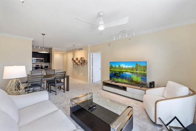 carpeted living room featuring ceiling fan, track lighting, and ornamental molding