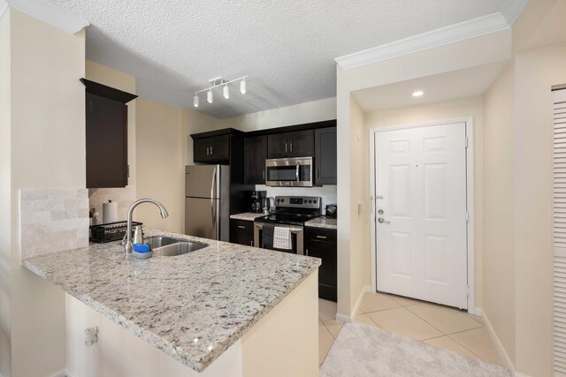 kitchen featuring sink, light stone counters, appliances with stainless steel finishes, kitchen peninsula, and track lighting