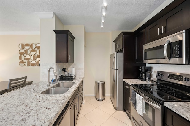 kitchen with appliances with stainless steel finishes, sink, backsplash, rail lighting, and a textured ceiling