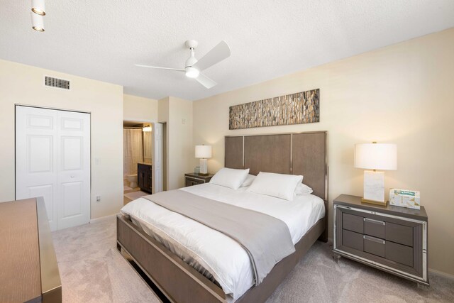 bedroom with ceiling fan, ensuite bathroom, a closet, and carpet flooring