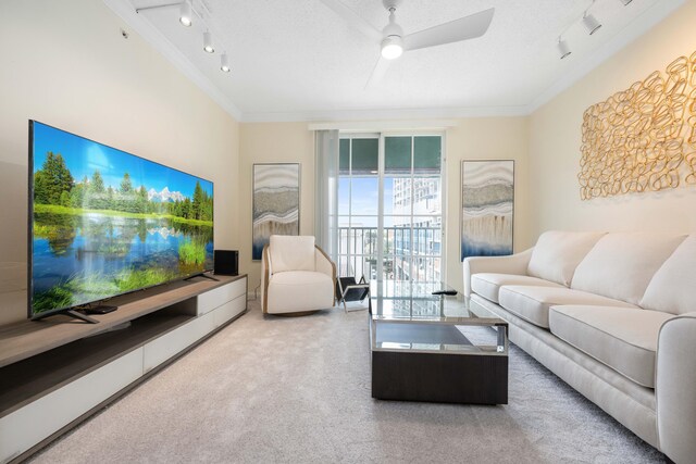 carpeted living room with a water view, ceiling fan, crown molding, and track lighting