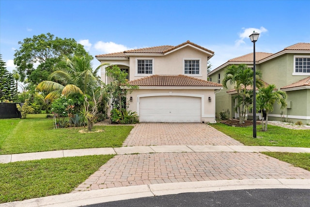 mediterranean / spanish house featuring a garage, a tile roof, decorative driveway, a front yard, and stucco siding