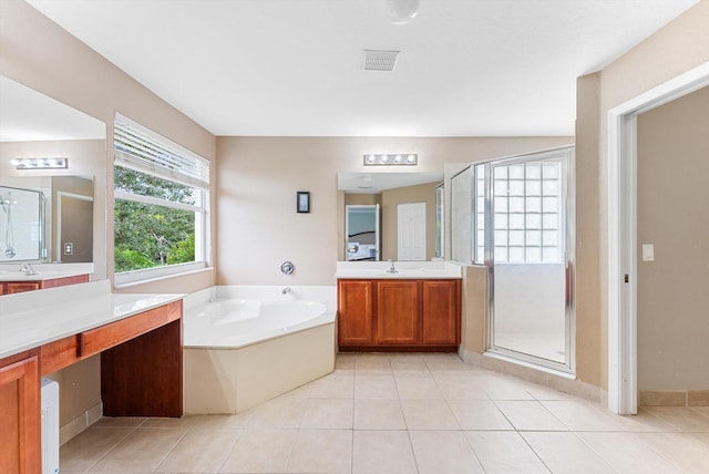 full bathroom featuring a sink, two vanities, a garden tub, and tile patterned floors