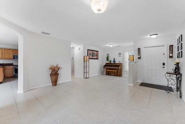 tiled foyer entrance with an inviting chandelier