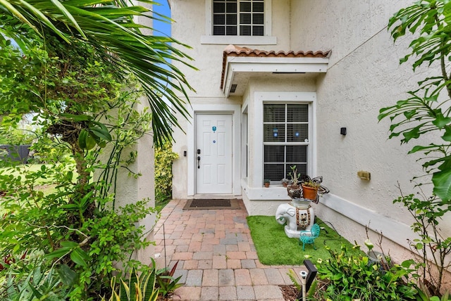 entrance to property featuring a tile roof and stucco siding