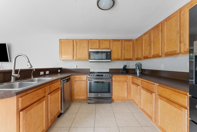 kitchen featuring dark countertops, appliances with stainless steel finishes, light tile patterned flooring, a sink, and a textured ceiling