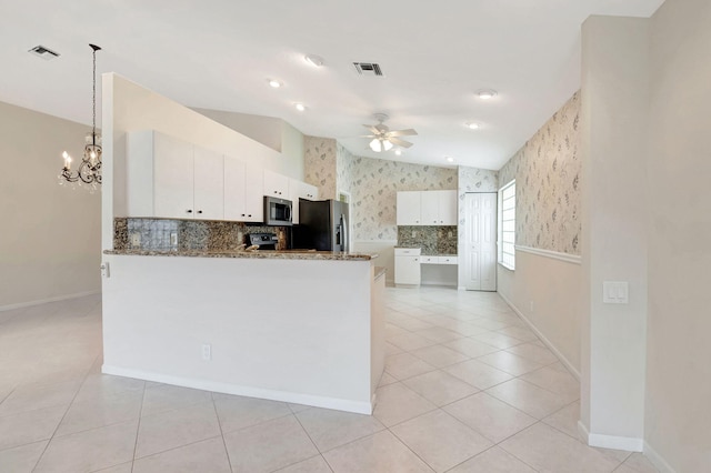 kitchen with stone counters, ceiling fan with notable chandelier, kitchen peninsula, white cabinetry, and stainless steel appliances