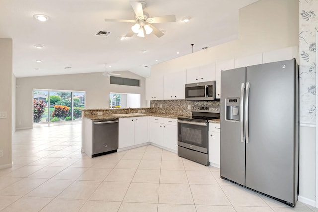 kitchen featuring white cabinetry, light stone countertops, kitchen peninsula, vaulted ceiling, and appliances with stainless steel finishes