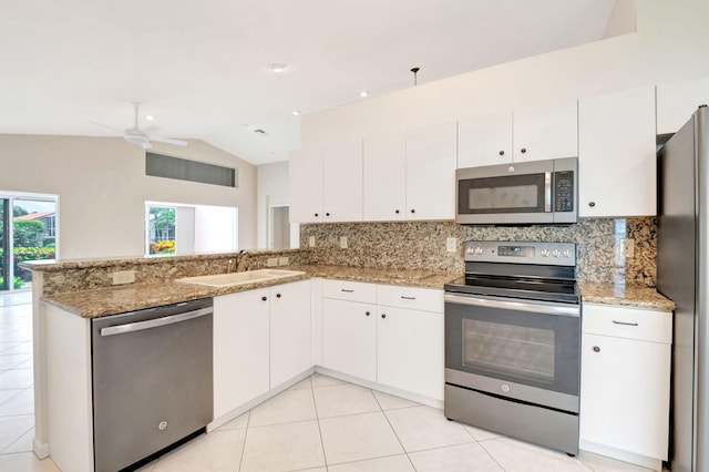 kitchen featuring sink, kitchen peninsula, vaulted ceiling, decorative backsplash, and appliances with stainless steel finishes