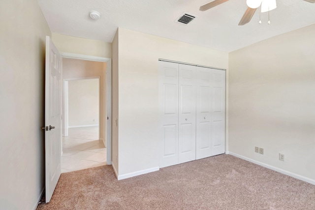 unfurnished bedroom featuring ceiling fan, light carpet, and a closet