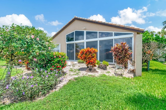 view of side of home with a yard and a sunroom