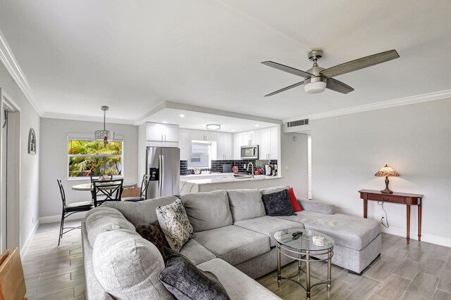 living room featuring crown molding, light wood-type flooring, and ceiling fan