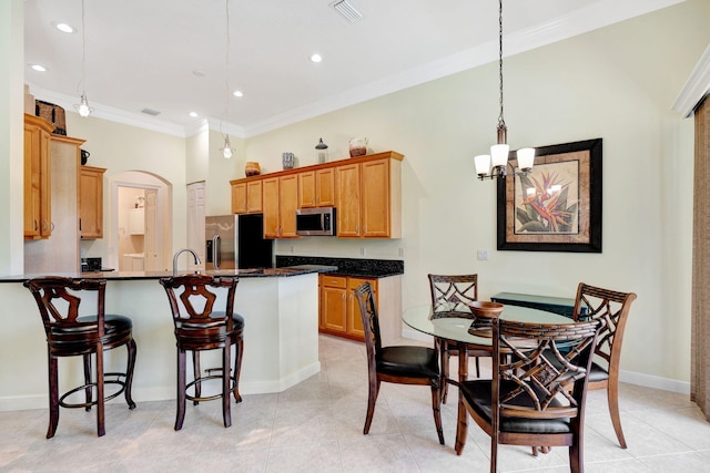 kitchen featuring crown molding, light tile patterned floors, an island with sink, decorative light fixtures, and stainless steel appliances