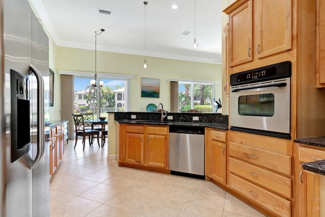 kitchen with a notable chandelier, dark stone countertops, plenty of natural light, pendant lighting, and appliances with stainless steel finishes