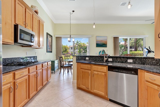 kitchen featuring sink, dark stone countertops, light tile patterned floors, decorative light fixtures, and stainless steel appliances