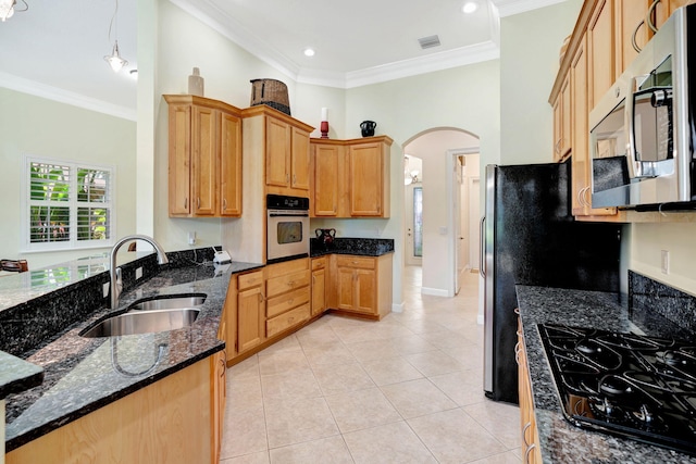 kitchen with dark stone countertops, ornamental molding, sink, and appliances with stainless steel finishes