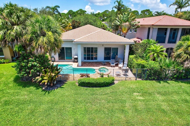 rear view of house with a lawn, a fenced in pool, and a patio