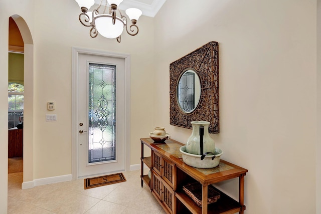 entryway with a chandelier, ornamental molding, and light tile patterned flooring