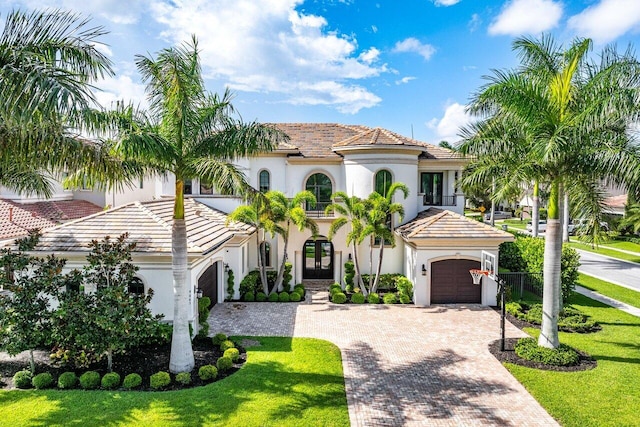 mediterranean / spanish home featuring a front yard and a garage