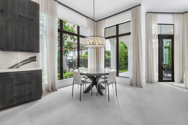 tiled dining room featuring a towering ceiling, a wealth of natural light, and a notable chandelier