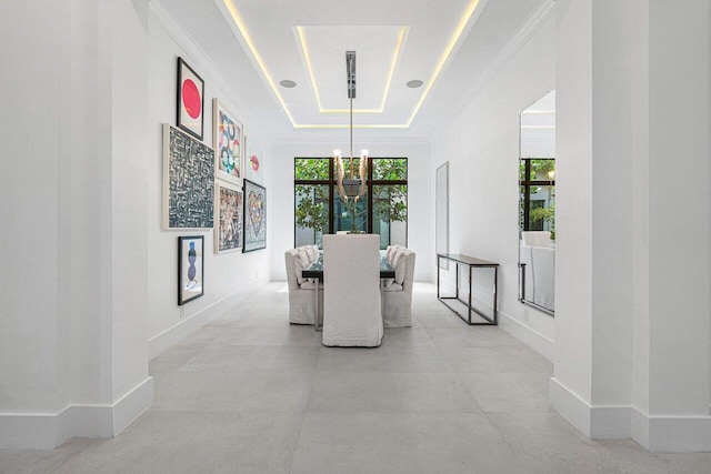 corridor featuring a tray ceiling and an inviting chandelier