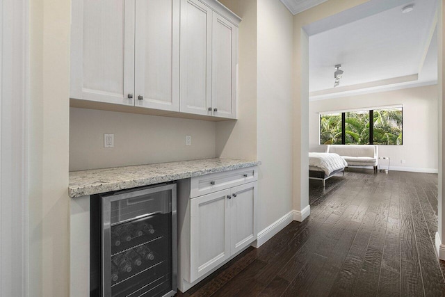 bar with white cabinetry, wine cooler, and light stone counters